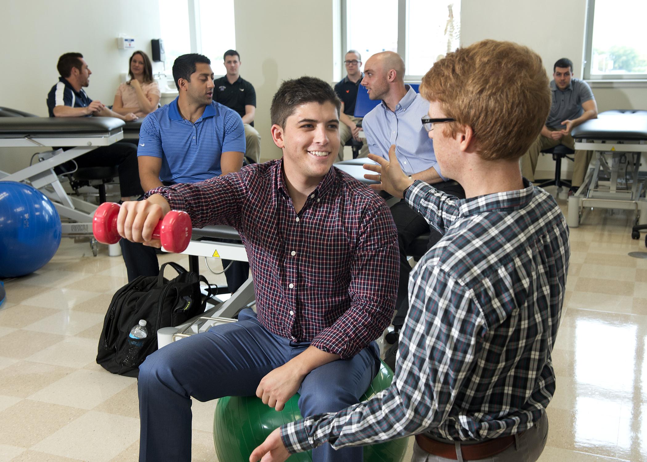 Physical therapy students demonstrating patient care with weights