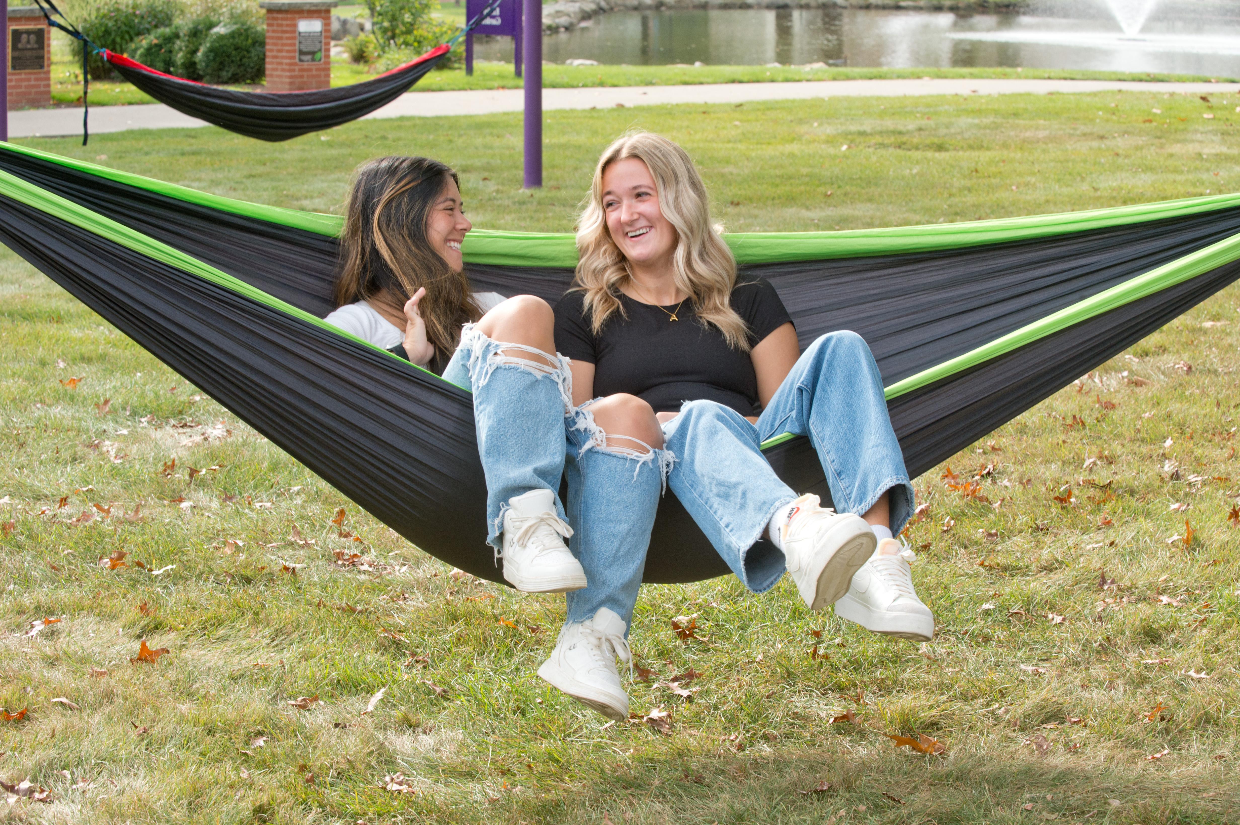 Smiling Mount Union students sitting together on a hammock at the Campus Lakes.